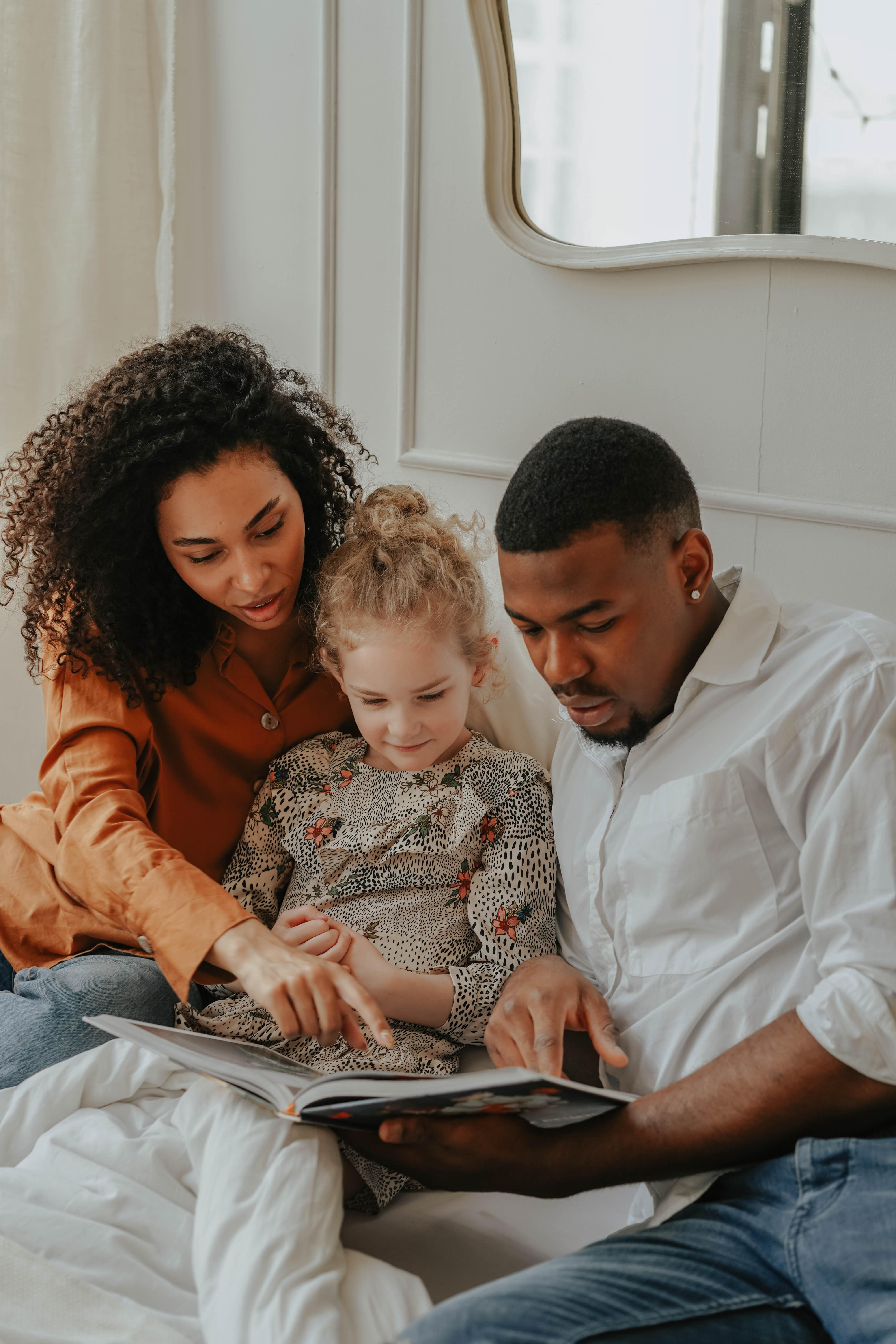 Woman pointing to story in book reading with child and man